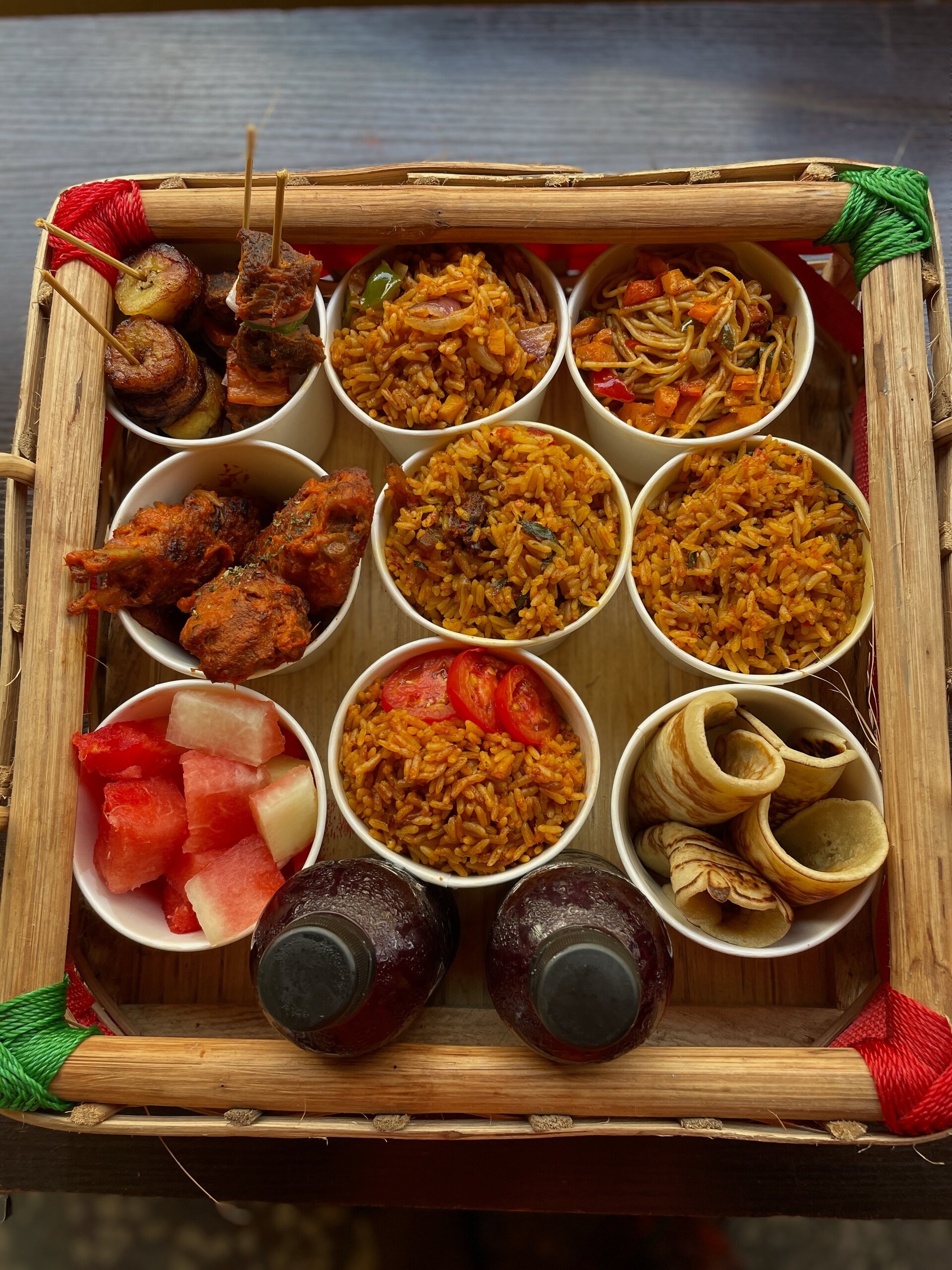A bamboo tray of jollof cups and small chops