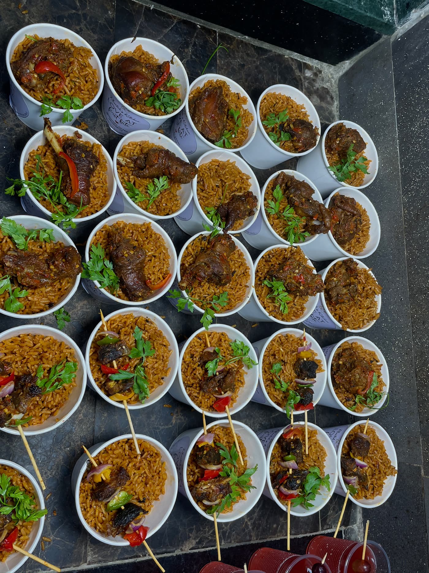 Cups of smoky jollof rice topped with chicken and suya